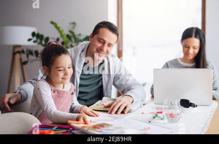 Parents with school girl indoors at home, distance learning and home office. Stock Photo