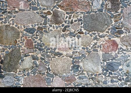 Аragment of an old stone wall, made of rough stones of different sizes. For use as abstract backgrounds and textures. Stock Photo