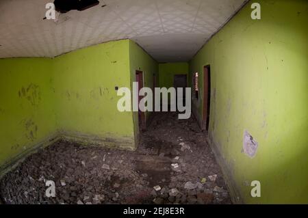 Abandoned house with green walls with dried mud on floor following flooding by mud lake environmental disaster which developed after drilling incident Stock Photo