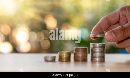 Human hands put silver coins into coins, financial concepts and business growth. Stock Photo