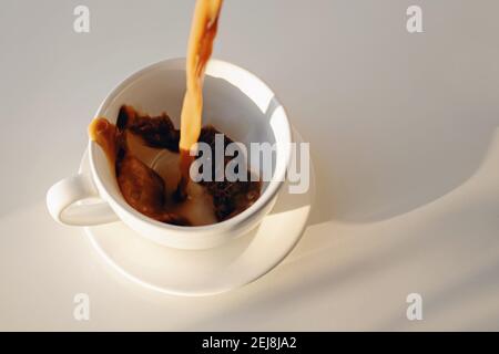 Pouring of coffee in a cup creating splash Stock Photo