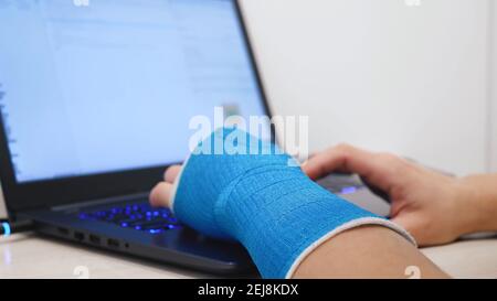 Fiberglass cast hand uses laptop program code Stock Photo
