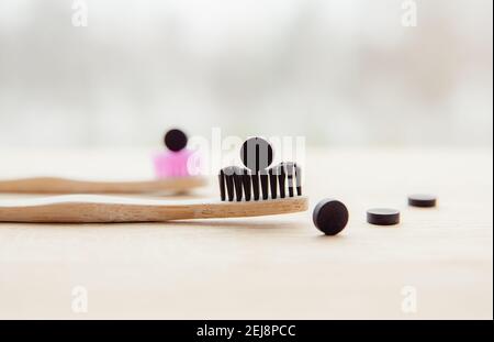 Side view of black activated charcoal toothpaste tablets. Dental care concept. Natural ingredients, side view of bamboo toothbrush with black. Stock Photo