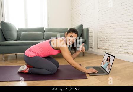 People exercising at home connected to online fitness class on laptop. Woman personal trainer coach on zoom teaching workout exercises in online body Stock Photo