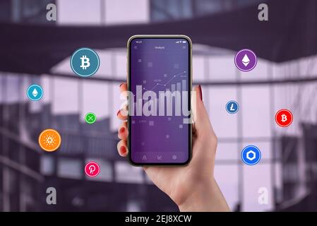 Concept of cryptocurrency market growth concept. Chart on smartphone in woman hand surrounded by cryptocurrencies Stock Photo