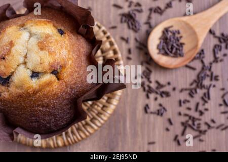 Overhead shot of chocolate muffin on wooden table with spoon and chocolate shavings, selective focus, horizontal, with copy space Stock Photo