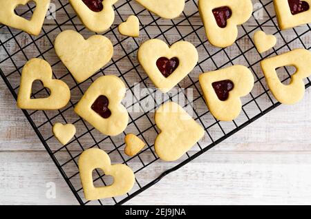 Vanilla and raspberry jam heart shaped cookies in a black rack. Stock Photo