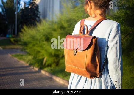 Girl wear leather fashion handmade bag. Leather backpack craft product. Stock Photo
