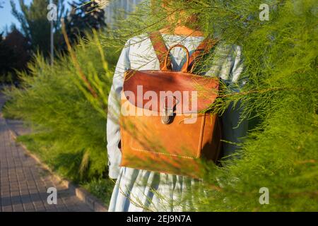 Girl wear leather fashion handmade bag. Leather backpack craft product. Stock Photo