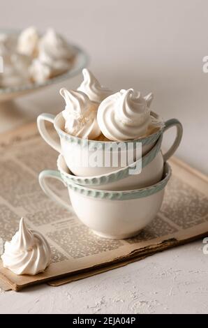 Meringue cookies in white and green tea cups on an old magazine. Stock Photo