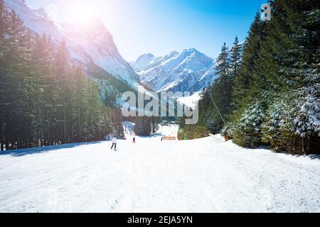 Mountain ski trail on the sunny day in sunlit with French Alps mountains peaks and fir forest Stock Photo