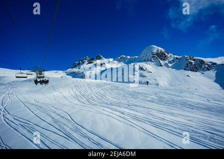 View from ski lift of High mountain panorama and clouds of French Alps tops covered with snow Stock Photo