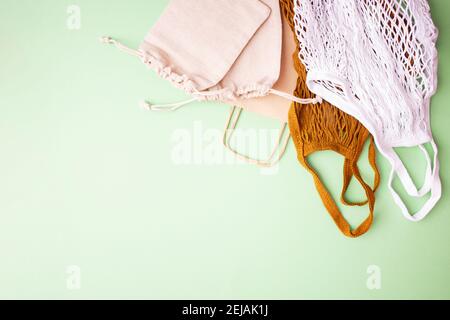 Canvas bags with drawstring, mockup of small eco sack made from natural cotton fabric cloth flat lay on green pastel background from top view Stock Photo