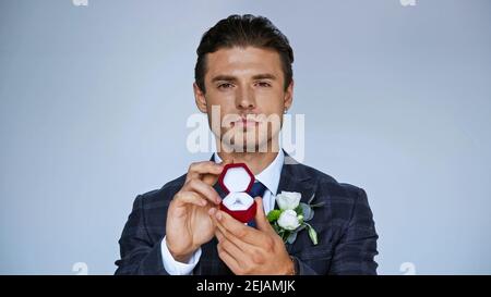 https://l450v.alamy.com/450v/2ejamjk/confident-groom-holding-jewelry-box-with-wedding-ring-isolated-on-blue-2ejamjk.jpg
