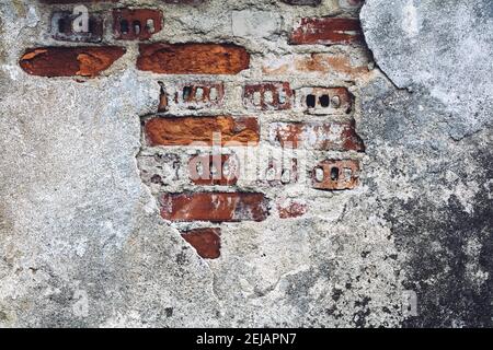Damaged old wall with bricks red showing through. Grunge background. Stock Photo