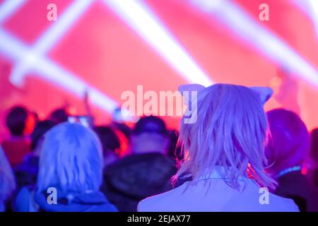 Pink hair teenage girl partying at rock concert in front of stage: back view Stock Photo