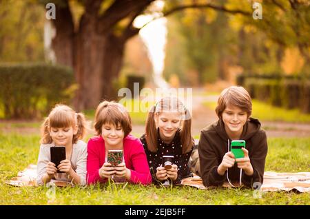 Smartphone addiction group of little children watching film movie cartoon together on digital tablet. Kids playing with phone together Stock Photo
