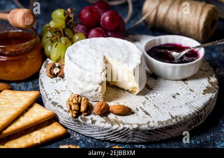 Camembert cheese close-up with honey, nuts, vine. Exquisite cheese plate, wine food. Camembert, bree. Soft french cheese. Italian food. Dairy products Stock Photo