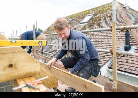 Workmen building a room in the roof on a residential property which used to be a bungalow. Stock Photo