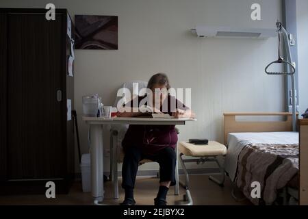 Patient in room, reading book, residential care home - Paris, France Stock Photo