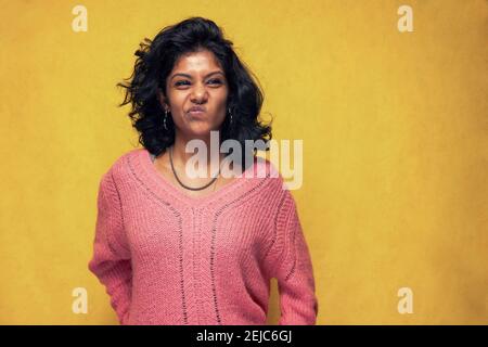 Beautiful Sri Lanka girl poses standing with yellow bright background- Young woman smiles making face Stock Photo