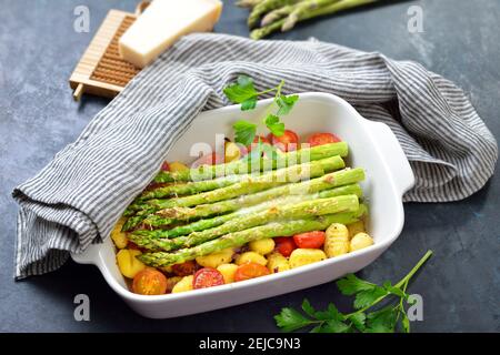 Green asparagus on Italian gnocchi with cherry tomatoes baked with grated parmesan cheese Stock Photo