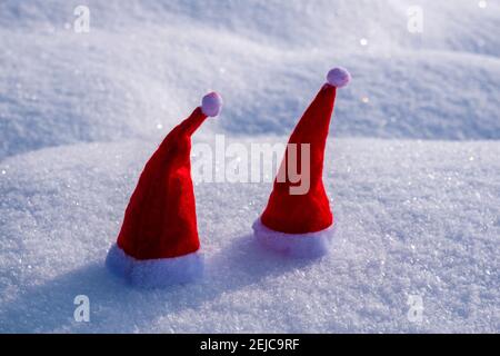 Two small red christmas caps placed on snow. Stock Photo