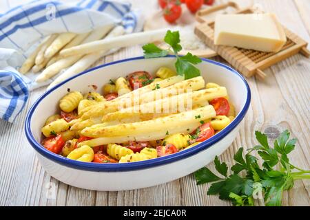 White asparagus on Italian gnocchi with cherry tomatoes baked with grated parmesan cheese Stock Photo