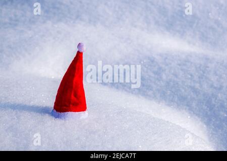 A small red christmas cap placed on snow. Stock Photo