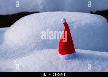 A small red christmas cap placed on snow. Stock Photo