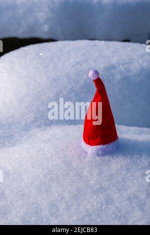 A small red christmas cap placed on snow. Stock Photo