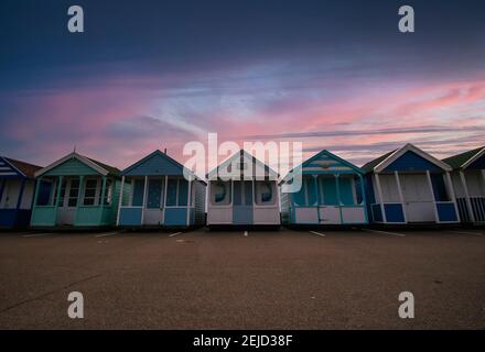 A row of colourful beach huts at dawn on the coast of Suffolk, UK Stock Photo