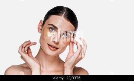 Woman applying eye patches under eyes isolated on white Stock Photo