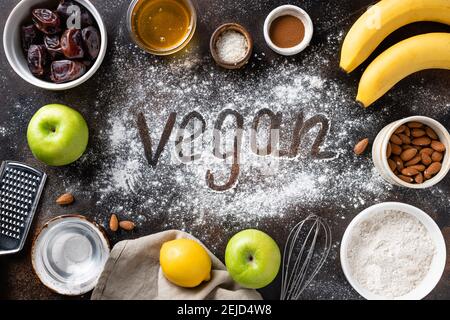 vegan baking ingredients, utensils and word Vegan on dark background Stock Photo