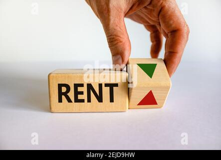 Rent level symbol. Businessman turns a wooden cube and changes the inscription 'rent up' to 'rent down'. White background. Business, interest rate, st Stock Photo