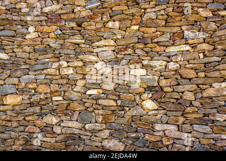 Natural stone wall made of various sizes and colors of rocks showcasing craftsmanship and texture Stock Photo