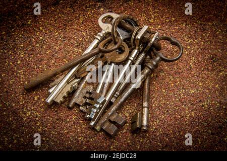Collection of antique keys scattered on a textured surface creating an interesting visual arrangement in warm hues Stock Photo