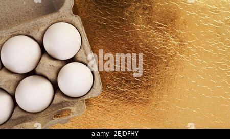 White chicken eggs in a cardboard tray on a gold background. Background with place for text. Healthy food and Easter concept. Protein food Stock Photo