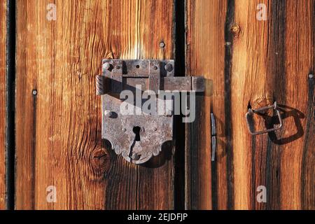 Handmade old lock on a weathered wooden door. Stock Photo