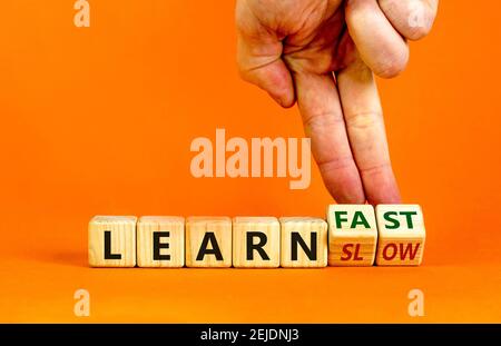 Learn slow or fast symbol. Businessman turns wooden cubes and changes words 'learn slow' to 'learn fast'. Beautiful orange background, copy space. Bus Stock Photo