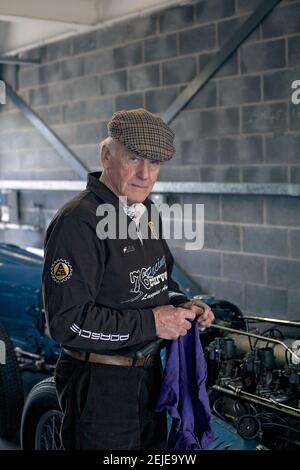 A senior man cleaning his hands after servicing his vintage car in the garage. Stock Photo