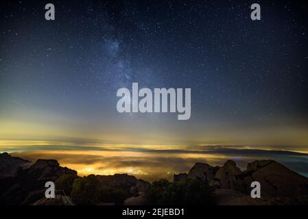 Night and Milky Way over Montserrat with fog, seen from the Sant Jeroni summit (Barcelona region, Catalonia, Spain) Stock Photo