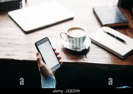 Man using phone inside a restaurant while drinking coffee Stock Photo