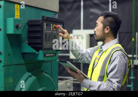 Close up hand of engineer or electrician man working check the electrical system with tablet at factory. Stock Photo
