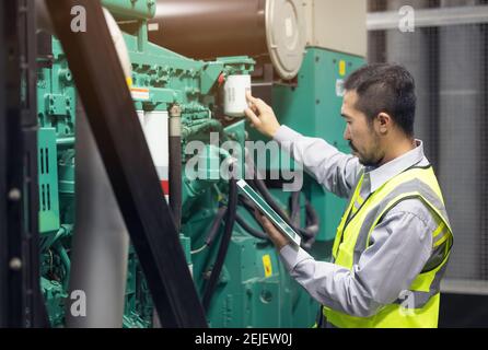 Close up hand of engineer or electrician man working check the electrical system with tablet at factory. Stock Photo