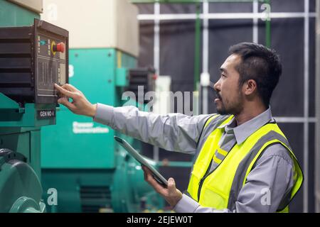 Close up hand of engineer or electrician man working check the electrical system with tablet at factory. Stock Photo