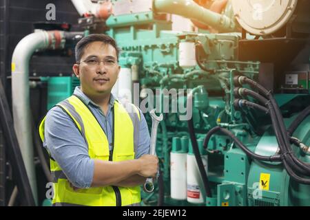 Portrait of worker or technician man hold wrench, smile and stand at generator room Stock Photo