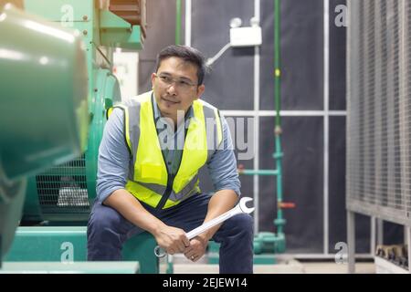 Portrait of worker or technician man hold wrench, smile and stand at generator room Stock Photo