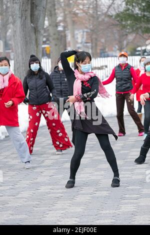 A slender graceful Chinese American woman leads a dance exercise class on a cold winter day. In a Flushing Queens, New York park. Stock Photo