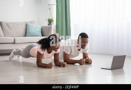 Sporty black couple having online fitness class, using laptop Stock Photo